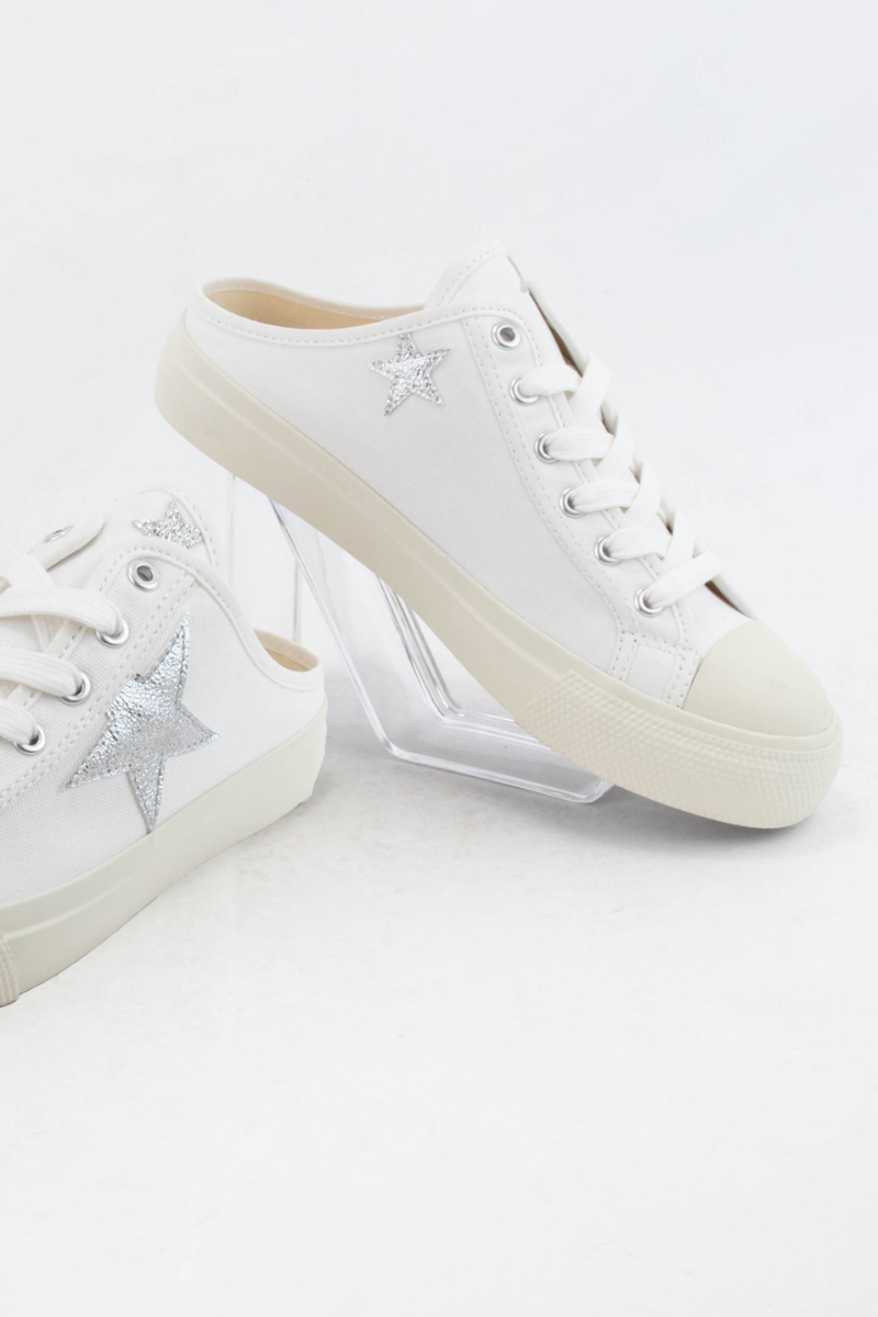 White lace-up slide sneakers with pale star accents and cream soles.