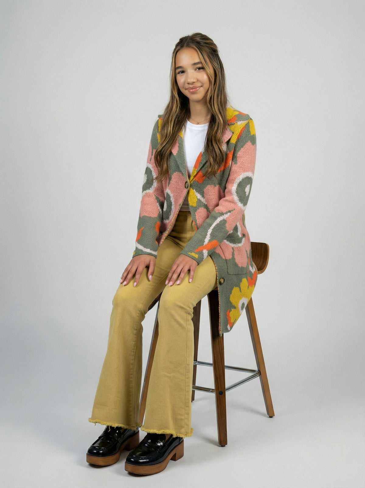 Golden yellow flared pants styled with a colorful floral cardigan.